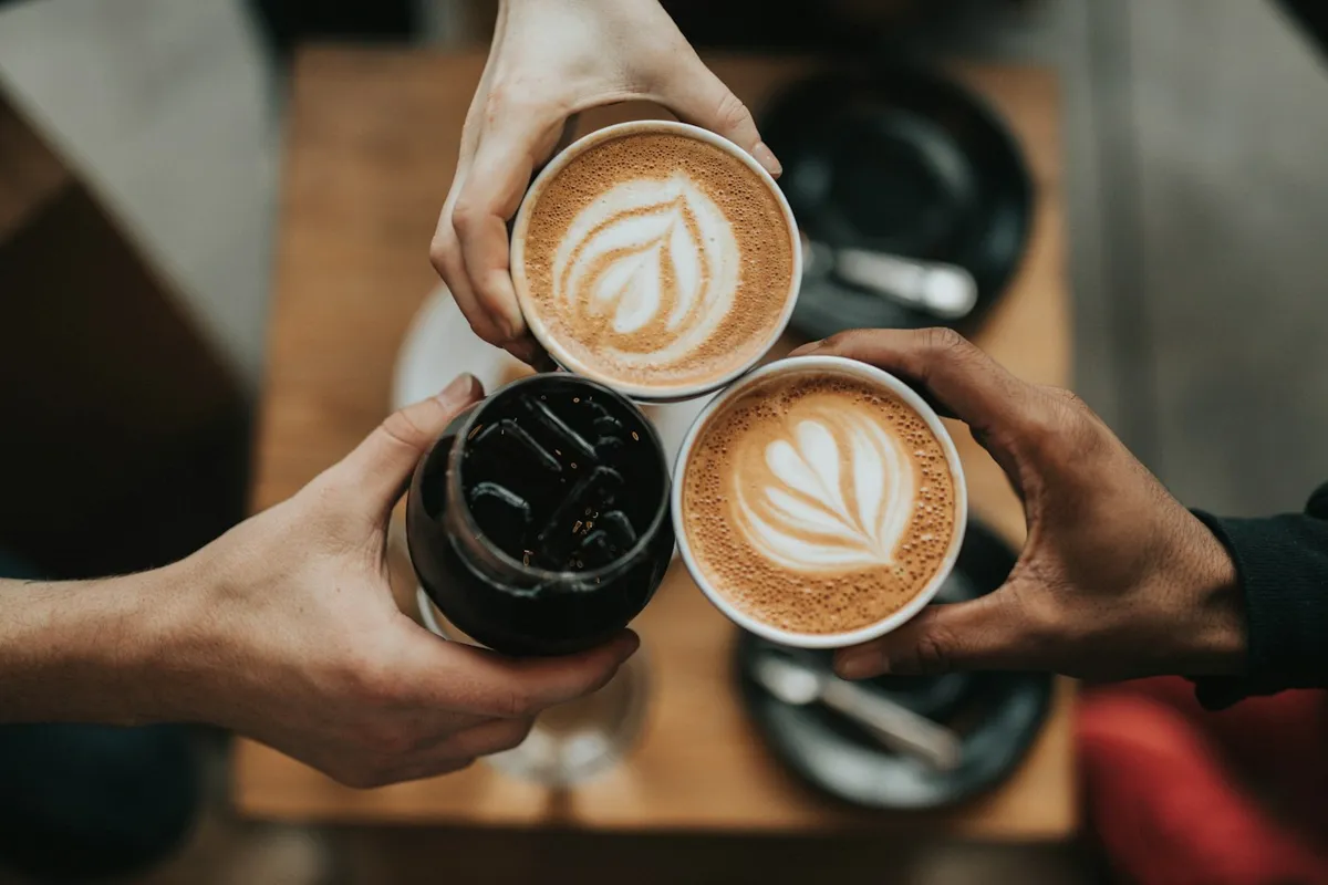 Three cups of coffee raised in a toast